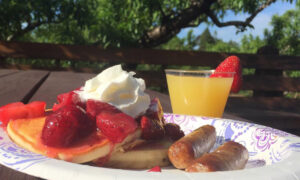 Pancake breakfast with strawberries, sausage, and cider mimosa