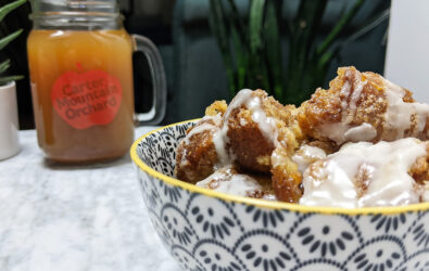Cider donut bread pudding in a bowl with an Carter Mountain Orchard mason jar mug and apple in background