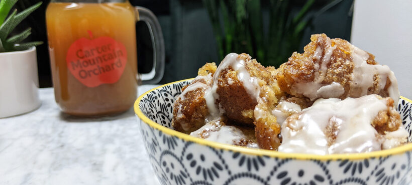 Cider donut bread pudding in a bowl with an Carter Mountain Orchard mason jar mug and apple in background