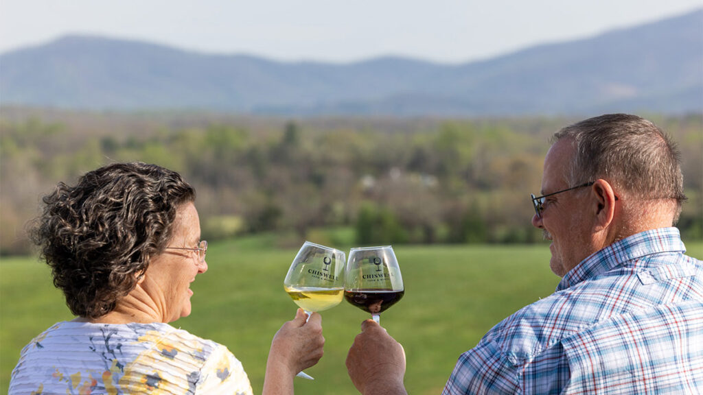 Cheers! A couple with wine glasses and a view of the Blue Ridge mountains