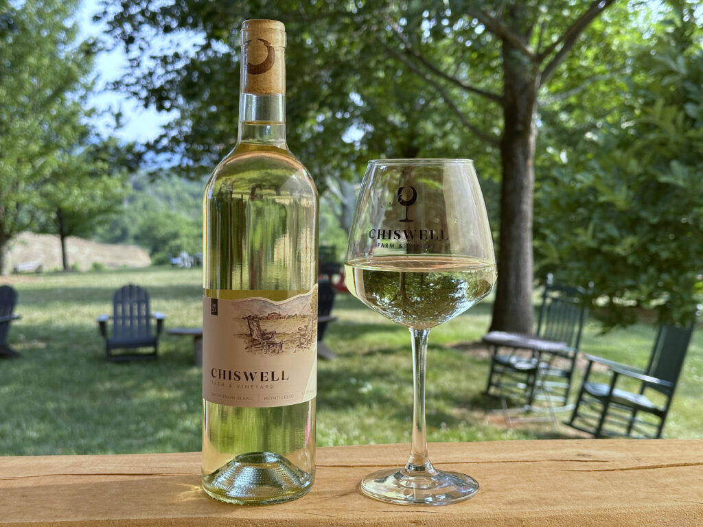 A bottle and glass of white wine outdoors