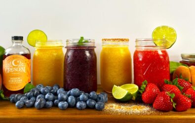 Peach daiquiri, displayed along with other daiquiris, blueberries, peaches, strawberries, limes and other ingredients