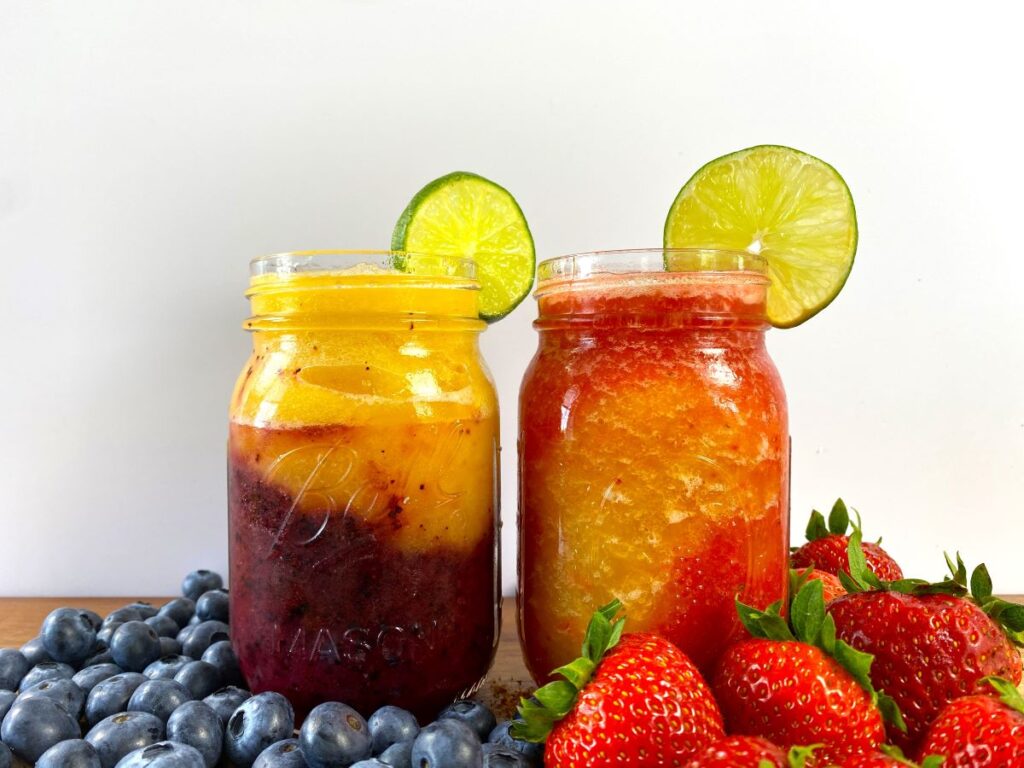 Two blended daiquiris, plus blueberries, strawberries, and lime slices