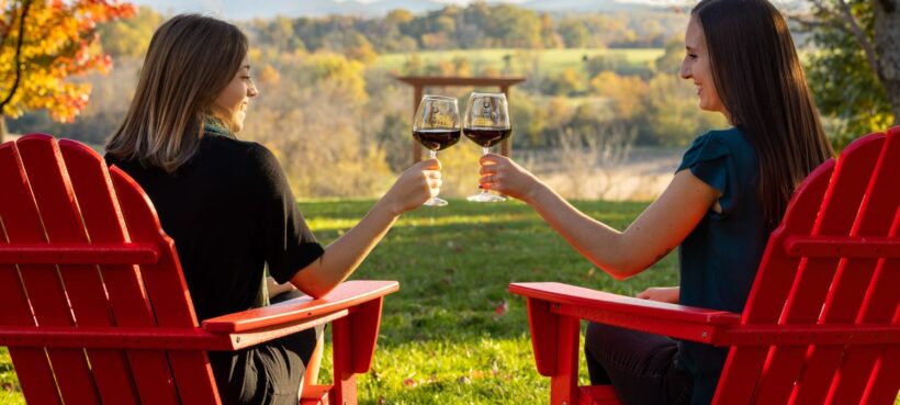 Red wine and red Adirondack chairs outdoors at Chiswell Farm & Winery