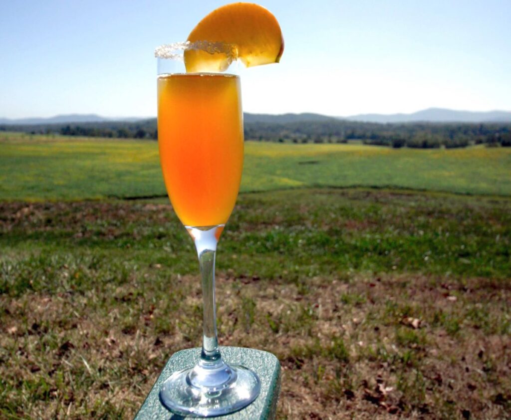 Chiswell's famous CiderMosa specialty drink resting on the arm of a chair in front of the beautiful central Virginia landscape.