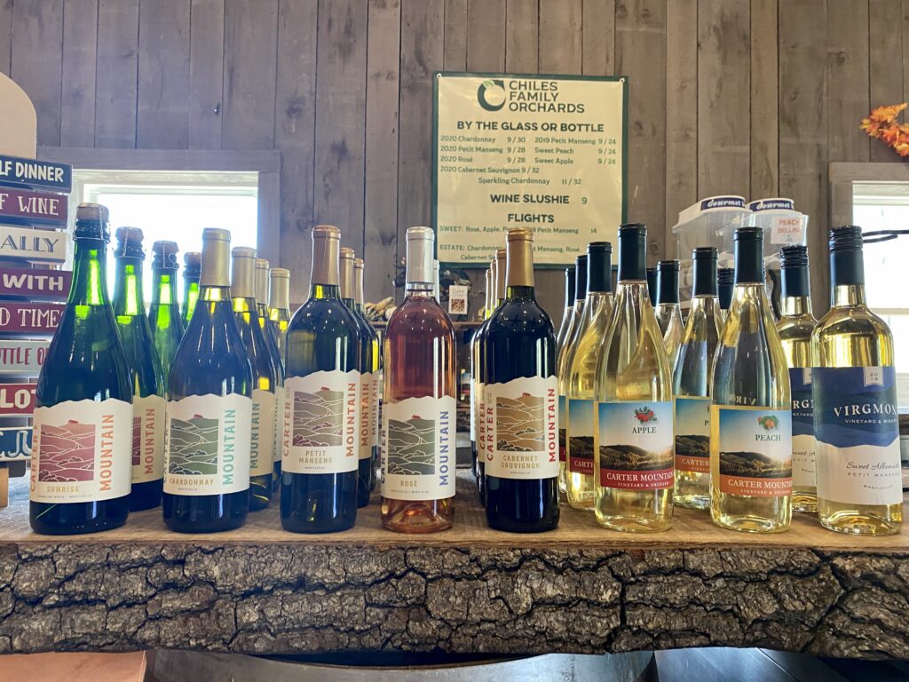 A lineup of Carter Mountain Wine bottles on a wooden bar at Chiles Peach Orchard.