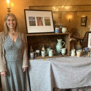 Pottery artist Laura Chatterson beside a display of her artisanal works.