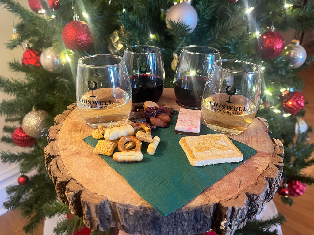 A holiday wine flight with festive pairings, in front of a Christmas tree.