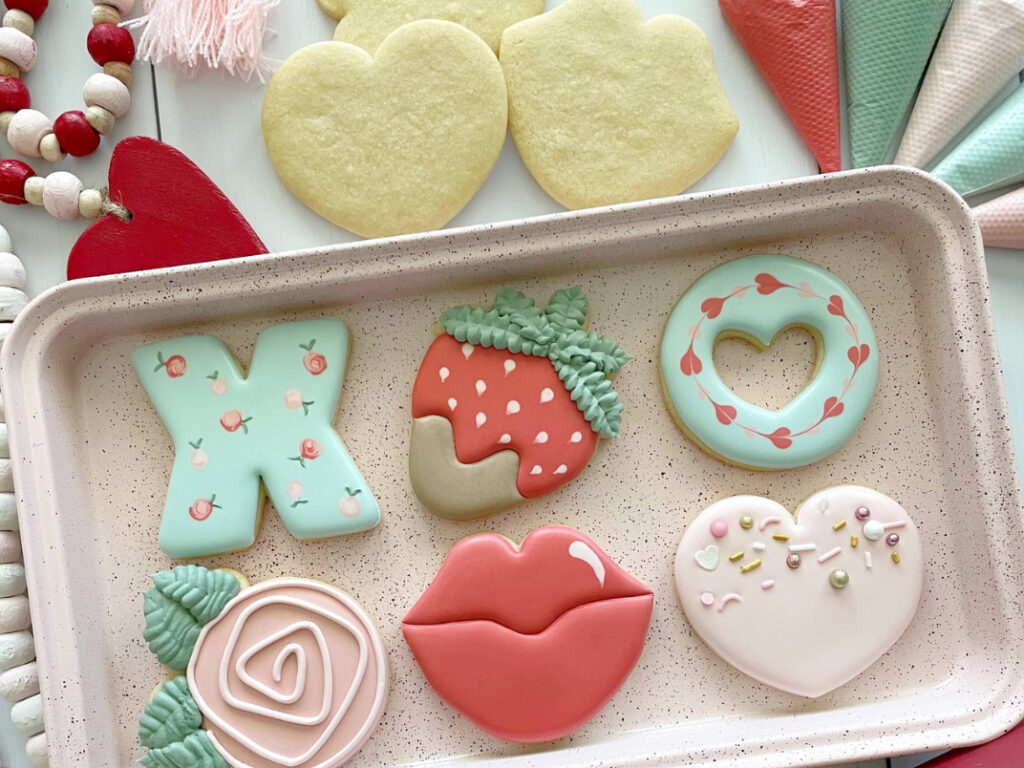 Valentine's Day sugar cookie designs, including lips, a rose, a strawberry, a heart, an X, and an O.