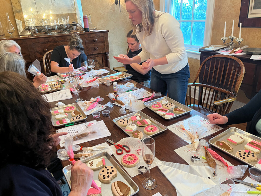 Jaclyn Shaffer and others decorate sugar cookies while drinking wine.