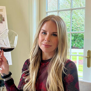 Tess Sherman, wine expert, seated and holding a glass of red wine.