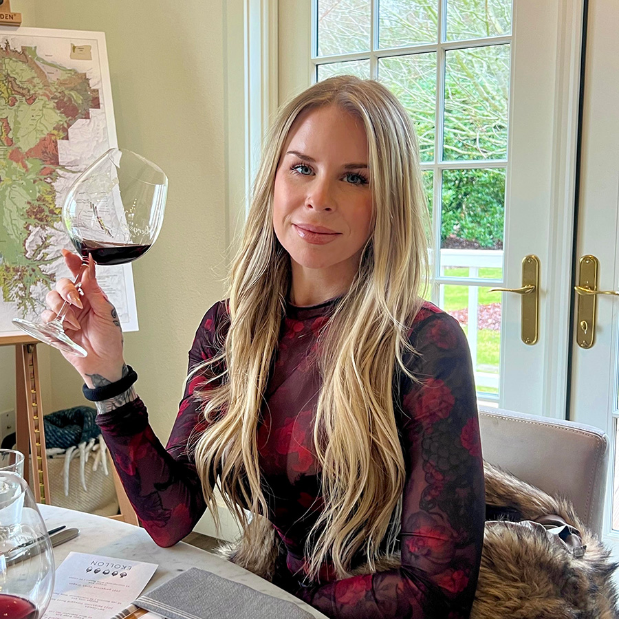 Tess Sherman, wine expert, seated and holding a glass of red wine.