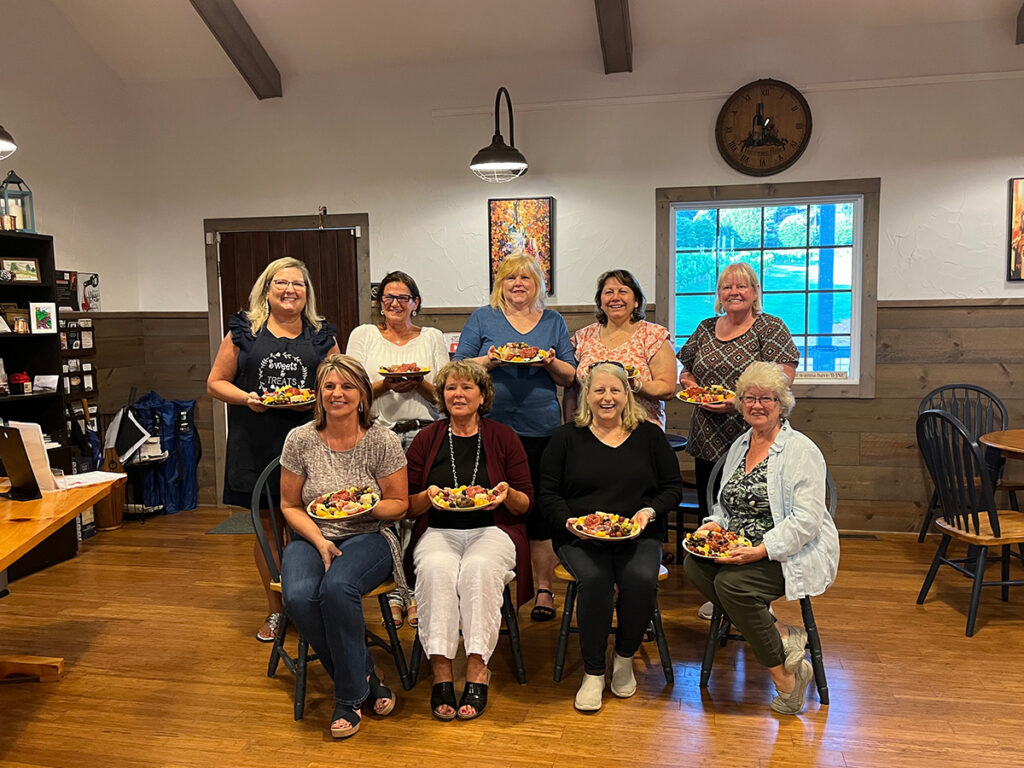 A group of women holding charcuterie boards.