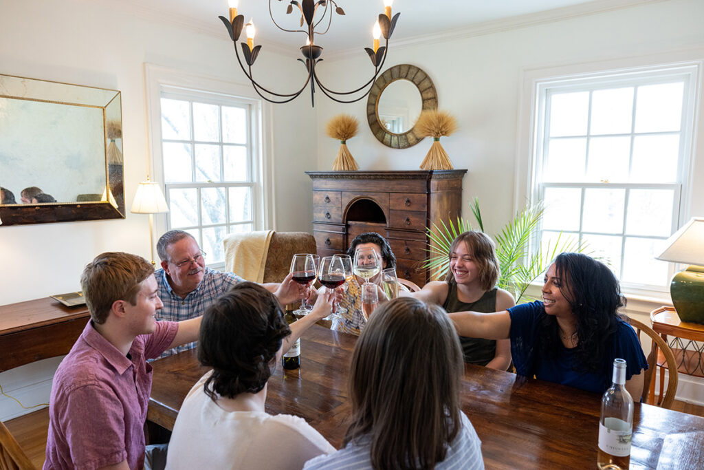 A group of people at a wooden table clinking wine glasses.