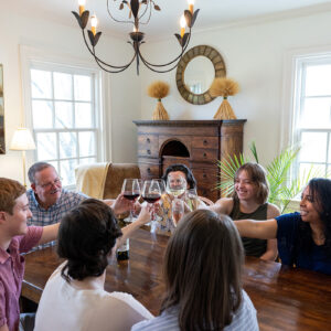 A group of people at a wooden table clinking wine glasses.