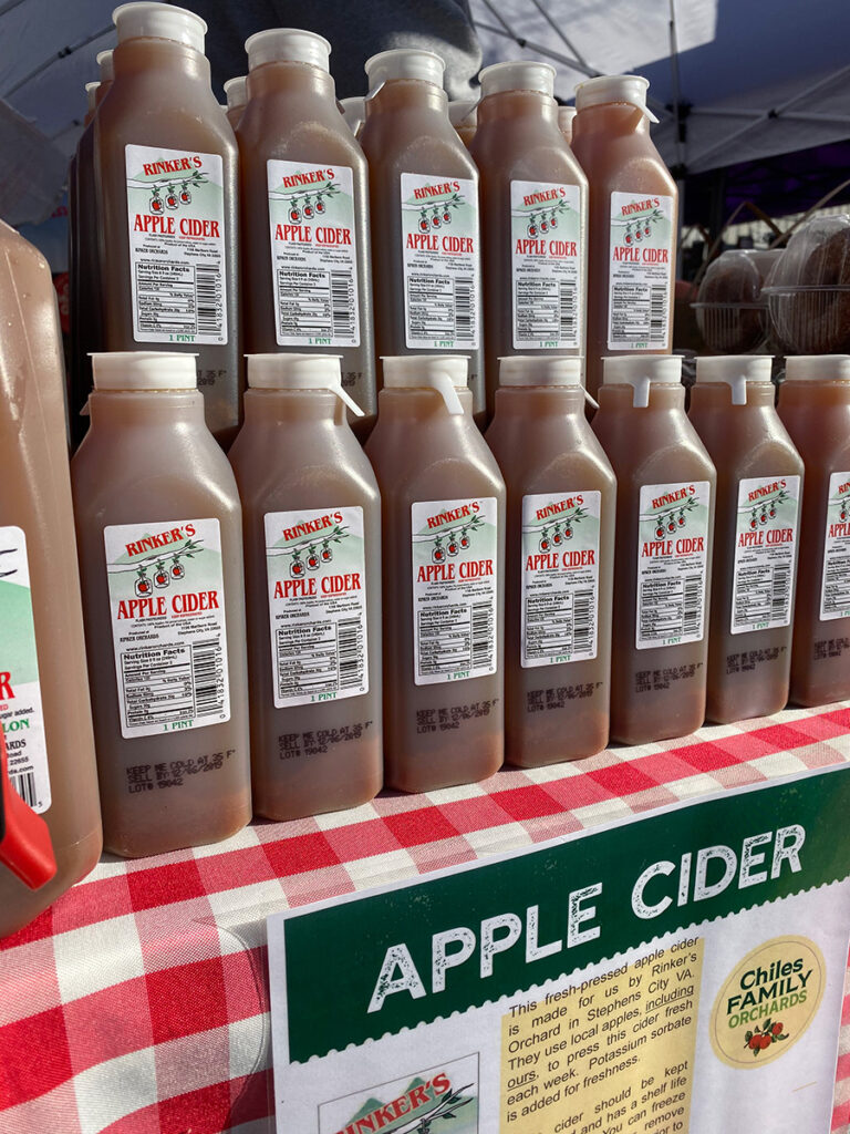 Jugs of apple cider on a gingham tablecloth.