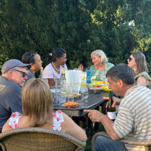 A group of people outside at a table enjoying wine and snacks at Chiswell