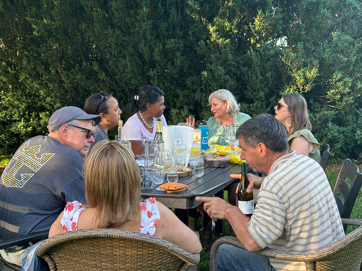 A group of people outside at a table enjoying wine and snacks at Chiswell