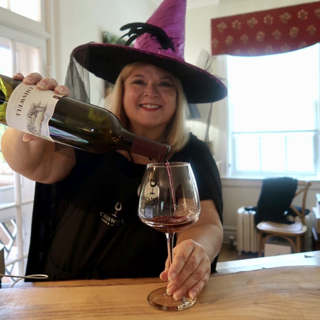 woman dressed as witch pouring wine