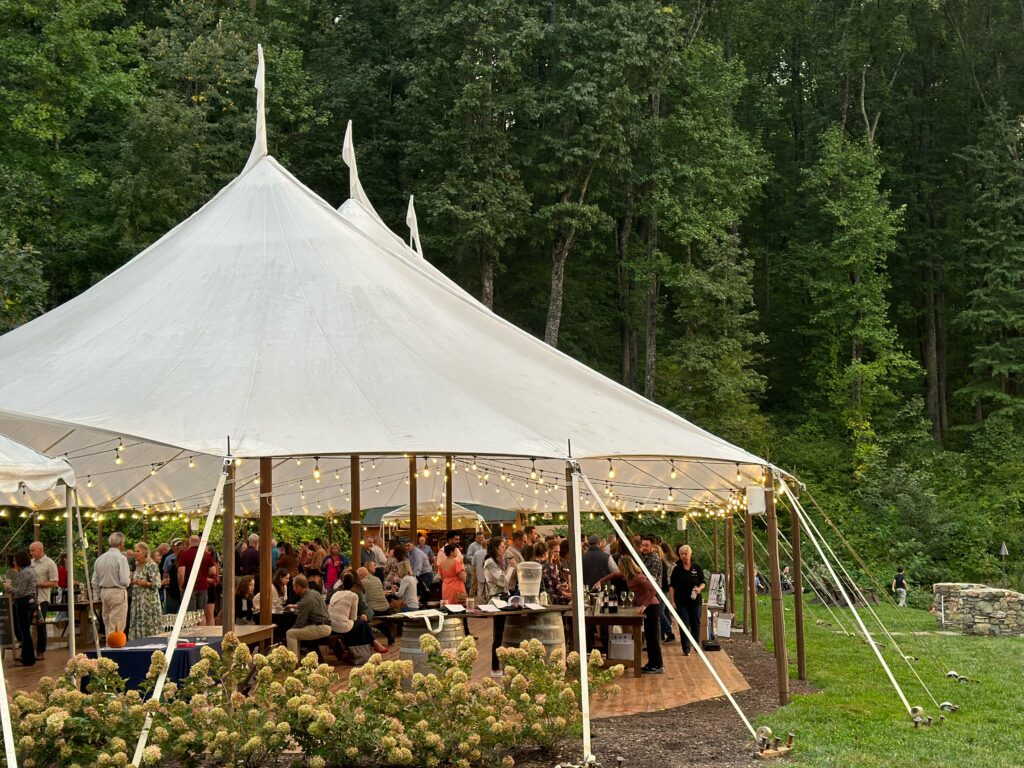 Guests at an event under a large outdoor pavillion.