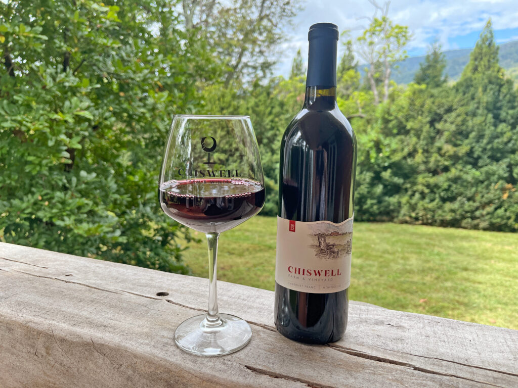 A bottle and glass of red wine outdoors