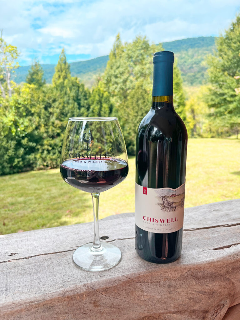 A bottle and glass of red wine outdoors