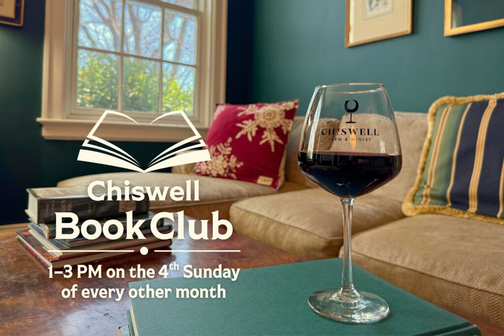 A glass of red wine wine on a table with books.