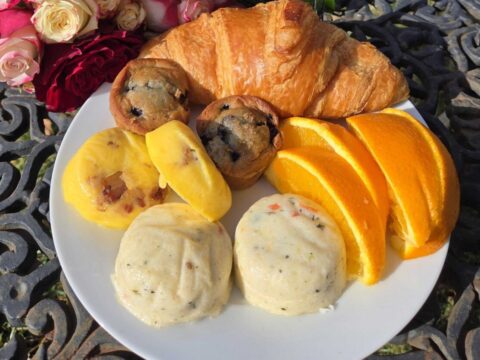 breakfast plate with croissants egg bites mimosas and flowers off to the side