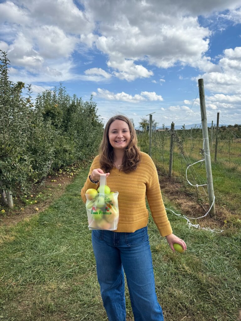 A girl holding a bag of apples in an apple orchard