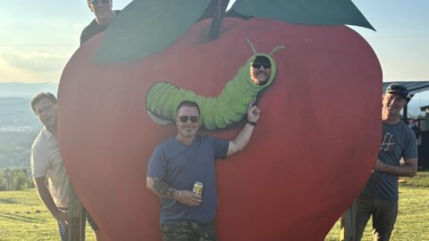 A group of men posing around a giant novelty apple