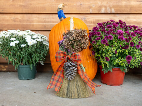 a lovingly decorated broom in front of a pumpkin