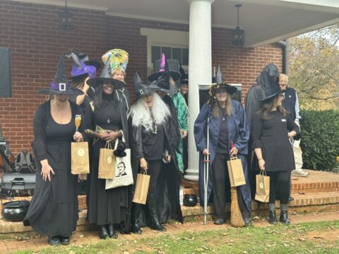 A group of women dressed as witches outdoors on a porch