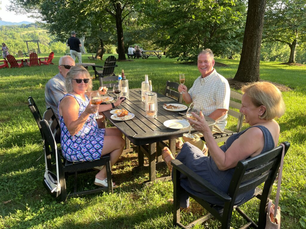 A group of people enjoying a picnic and wine outdoors