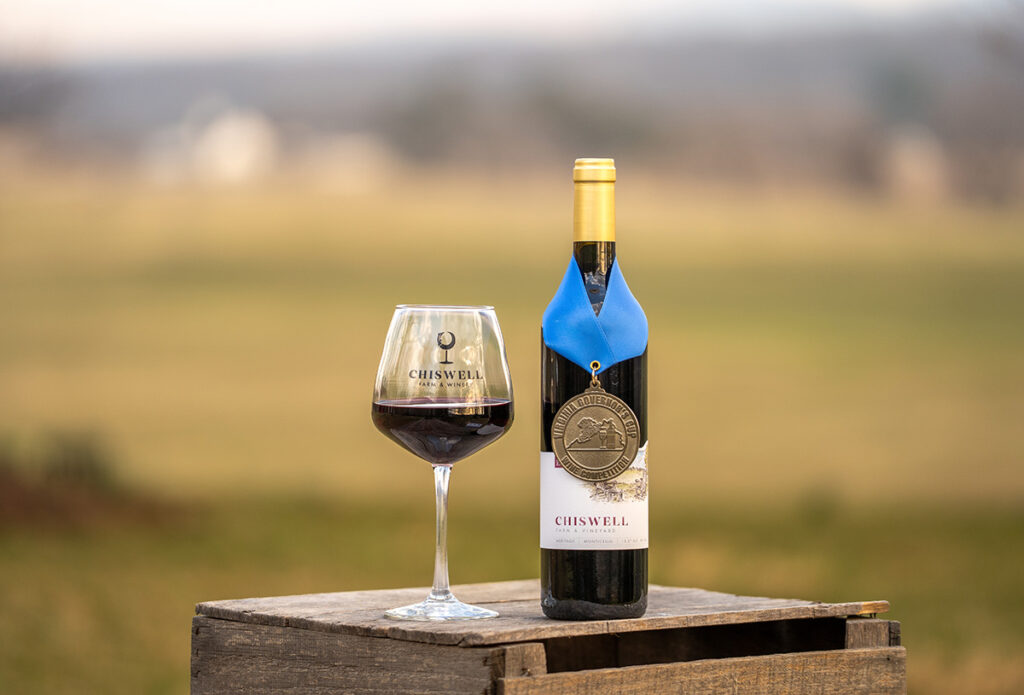 A wine glass and a bottle of red wine with an award on it