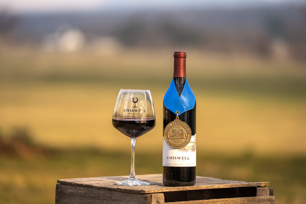 A wine glass and a bottle of red wine with an award on it