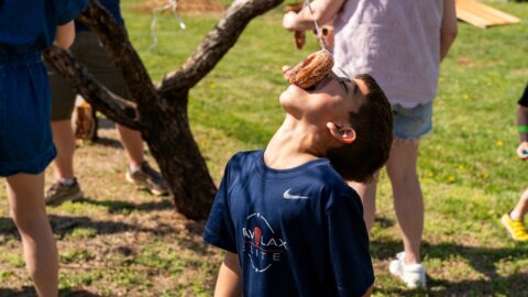 little kid bobbing for a peach cider donut