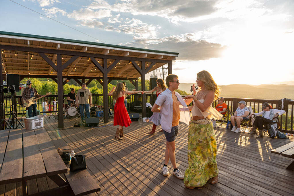 Dancers enjoying live music on a wooden deck at sunset