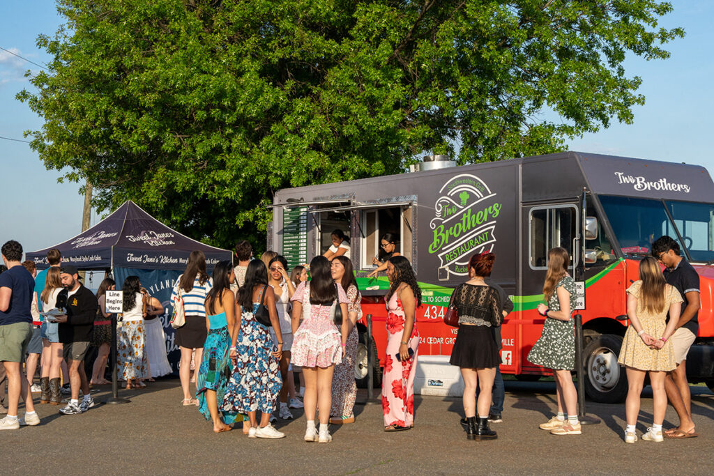 People lining up for food trucks at sunset