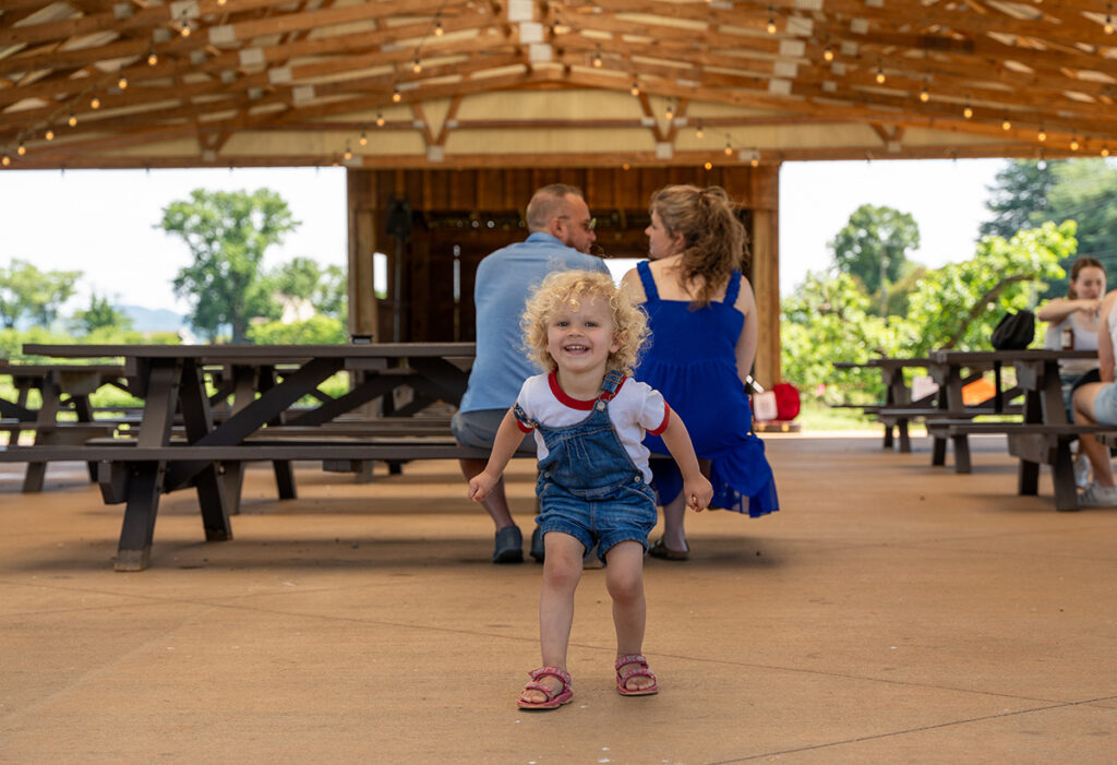 A child excitedly looking in the camera at an outdoor venue