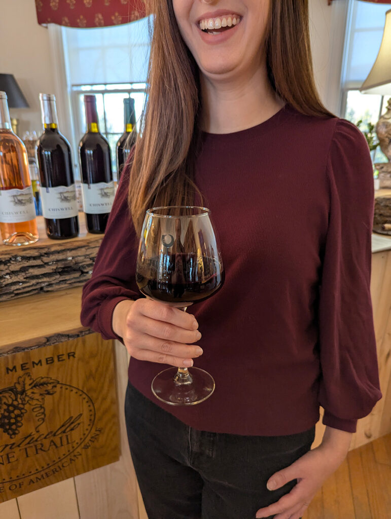 A person at a wine bar holding red wine