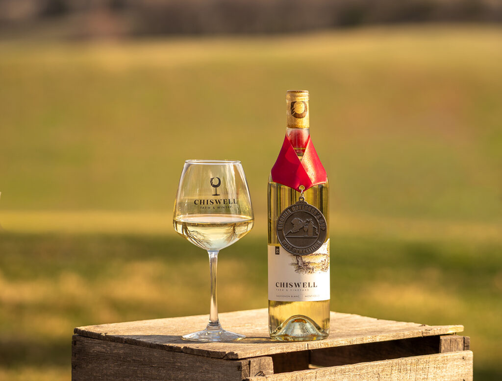 A bottle and glass of white wine outside