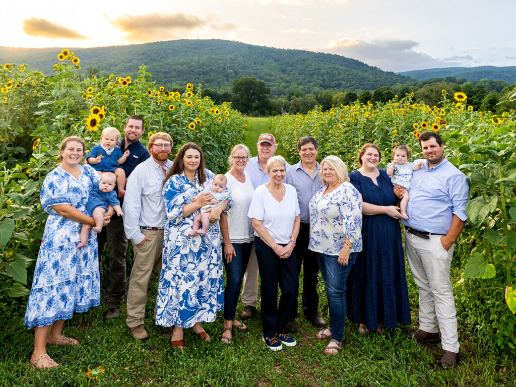 The extended Chiles family, including partners and babies, among the sunflower fields at evening