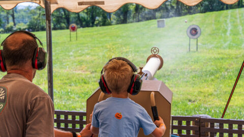 A boy and his father using a compressed air apple cannon
