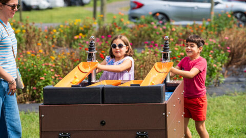 Two kids racing rubber ducks down ramps outdoors