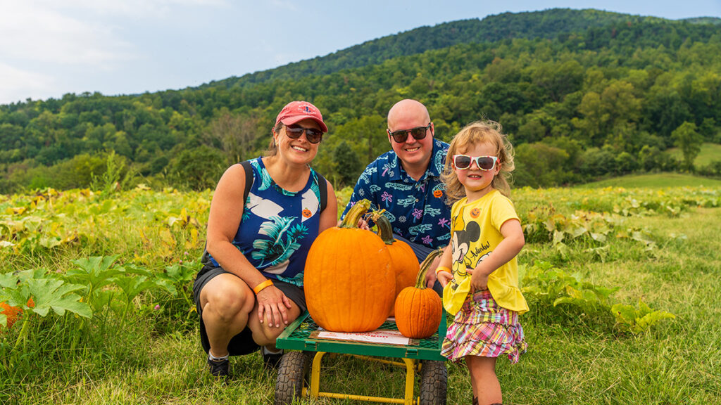 A family with pumpkins on a cart in a pumpkin patch