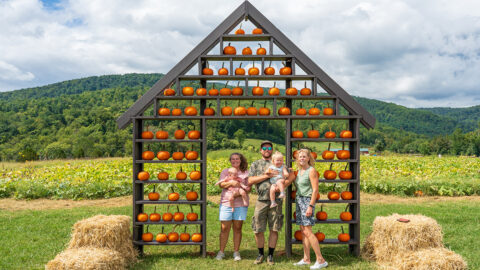 A family posing beneath an arrangement of pumpkins